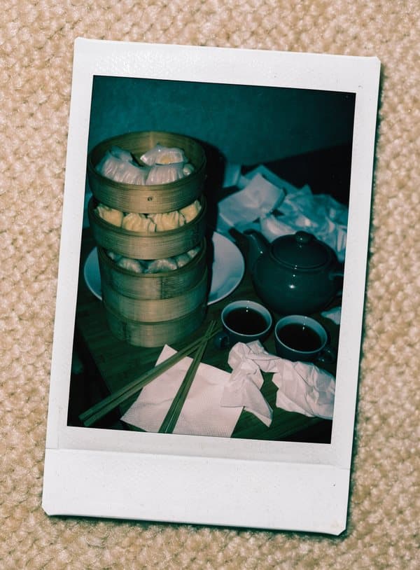 Polaroid av ett yum cha-bord med bambukorgar, tekanna och koppar
